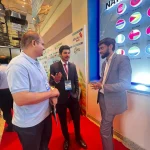 Two men talking in front of an exhibition booth at the ICCD event