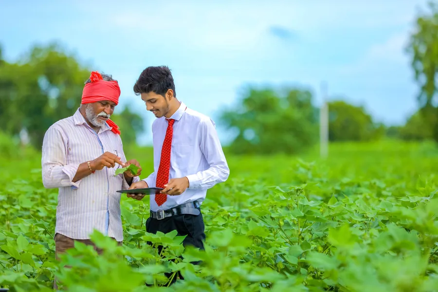 Two farmers reviewing crop data on a tablet in a green field